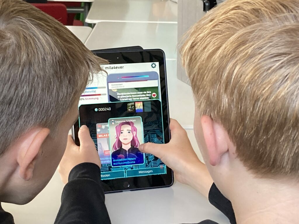 Zwei Kinder sitzen an einem Tisch und nutzen ein Tablet. Auf dem Tablet-Bildschirm wird eine virtuelle Chat-App mit einem digitalen Avatar und verschiedenen Textblöcken angezeigt. Beide Kinder konzentrieren sich auf den Bildschirm und zeigen Interesse an den digitalen Inhalten.
