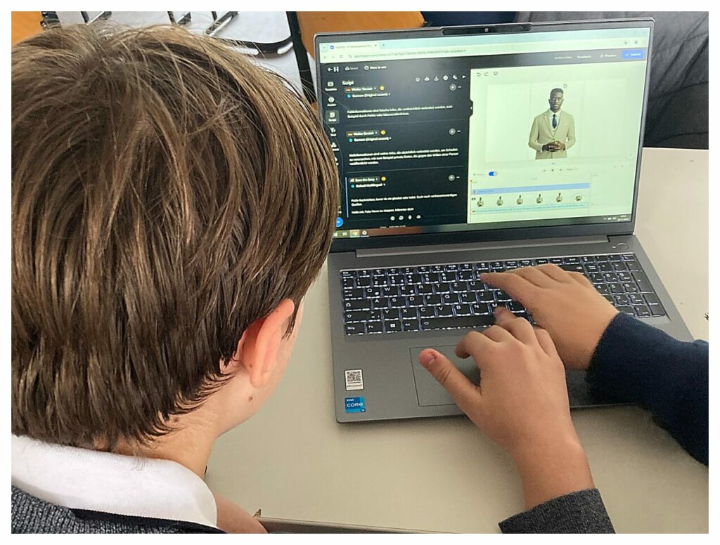 Ein Kind benutzt einen Laptop, auf dessen Bildschirm die Hand einer anderen Person zeigt. Auf dem Computer läuft eine Videobearbeitungssoftware, in der eine Person in einem Video spricht. Die Zeitleiste und die Chat-Funktion der Software sind sichtbar.