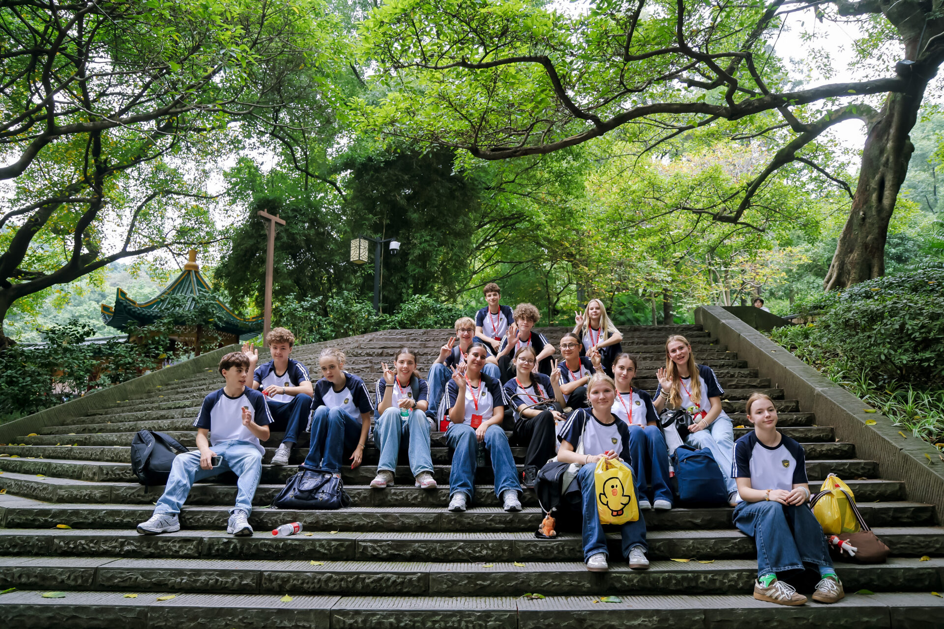 Eine Gruppe von Schülern in einheitlichen marineblauen und weißen Hemden sitzt auf den Steinstufen eines Parks und posiert für ein Foto.